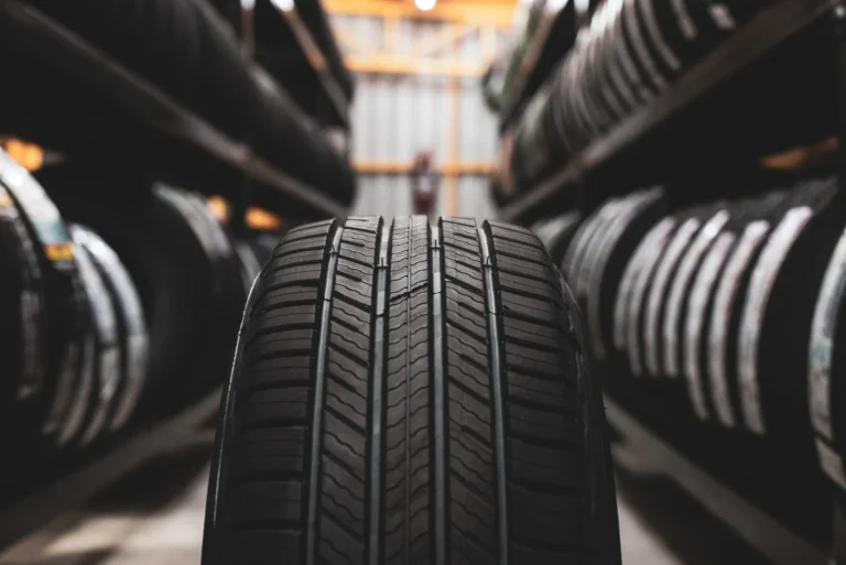 New tires aligned on racks in industrial warehouse.